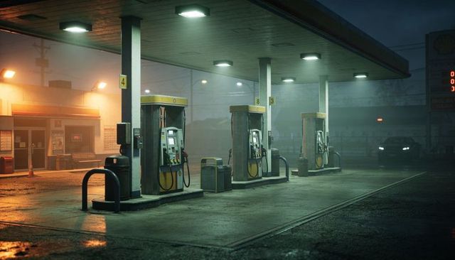 Nocturnal gas station forecourt glowing under canopy with wet reflective pavement