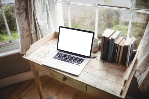 Transparent laptop and books near sunlit window table
