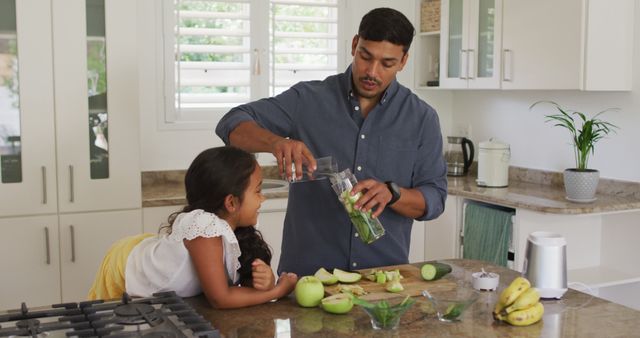 Hispanic father with smiling daughter teaching making cucumber water in kitchen. at home in isolation during quarantine lockdown.