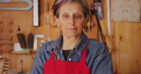 Senior Female Luthier in Workshop with Tools and Red Apron