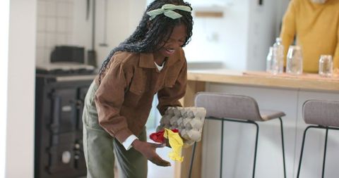 African american daughter crafting with egg carton and tissue paper at kitchen island