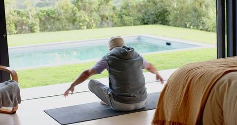 Senior man practicing yoga in peaceful home setting by poolside
