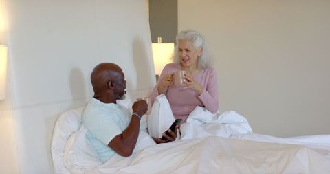 Senior Couple Enjoying Morning Coffee in Bed, Conversing