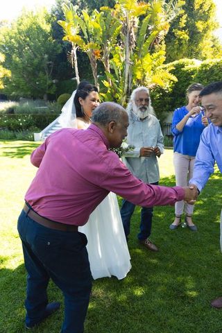Garden wedding greeting moment bride with guests shaking hands and celebrating outdoors