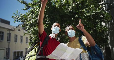 Two Male Friends Using Map in City During Pandemic