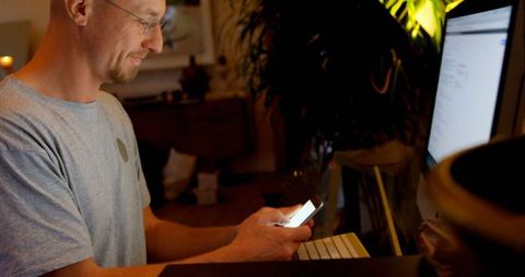 Man using mobile phone while working on desktop