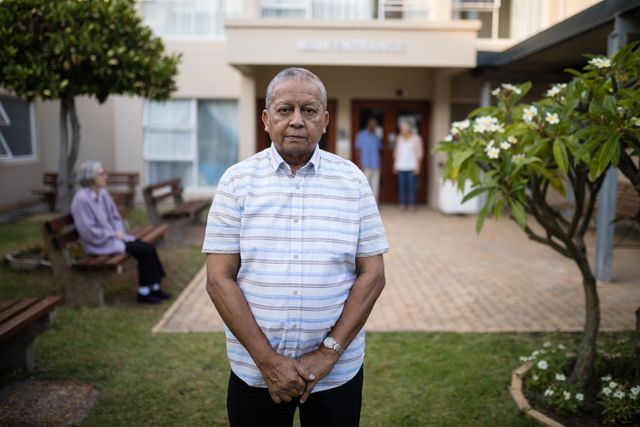 Portrait of senior man standing against friends at retirement home