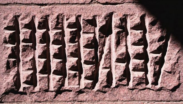 Textured carved sandstone panel showing vertical flutes and chisel-mark relief pattern