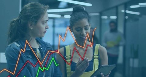 Businesswomen analyzing data on tablet in modern office setting