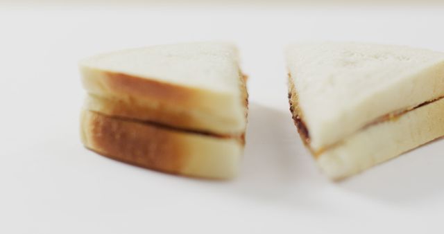 Image shows a close-up of a simple cut sandwich filled with peanut butter and jelly, perfect for food blogs, recipe websites, or promoting convenient snack ideas. Ideal for illustrating concepts related to lunchtime meals, kids' favorite snacks, or easy-to-make recipes.