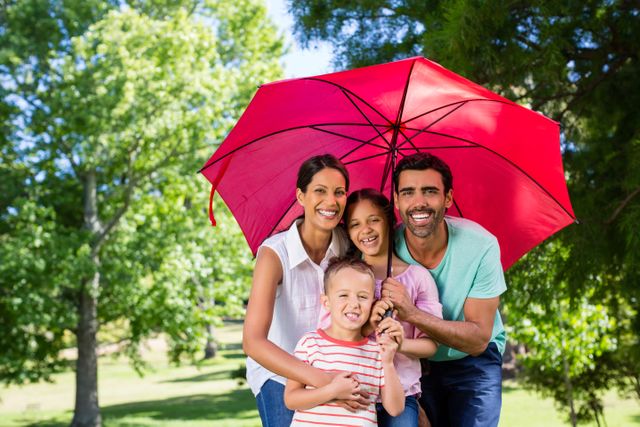 Happy Family Enjoying Time Together Under Red Umbrella in Park - Download Free Stock Photos Pikwizard.com