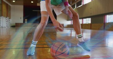 Female athlete dribbling basketball on hardwood gym floor with motion blur and reflections