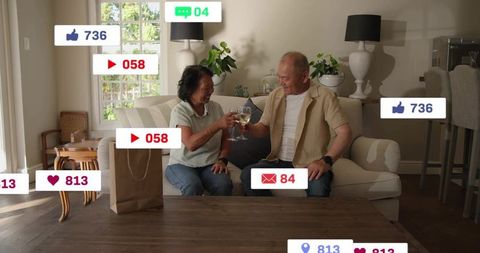 Mature couple toasting wine on living room sofa with social media notification overlays