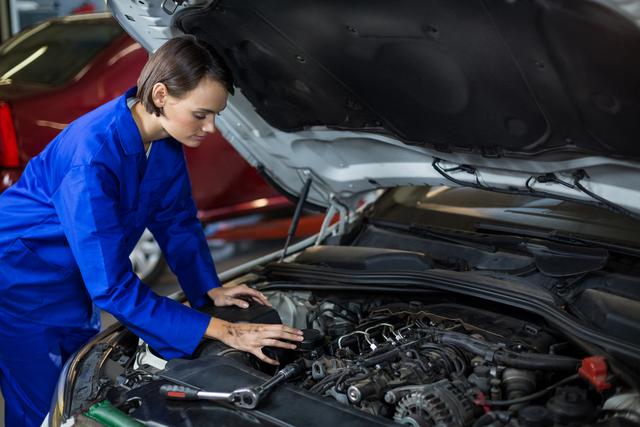 Female mechanic examining a car in repair garage