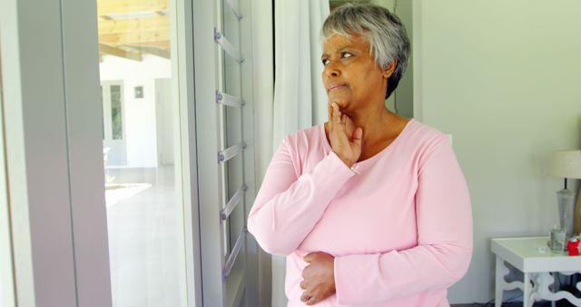 Contemplative Senior Woman Gazing Out Window in Pink Sweater - Download Free Stock Images Pikwizard.com