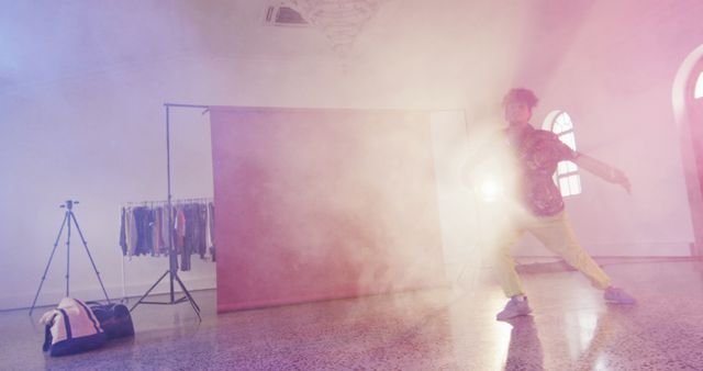 Professional biracial male dancer dancing with smoke trails in dance studio. Activity, lifestyle and dance concept.