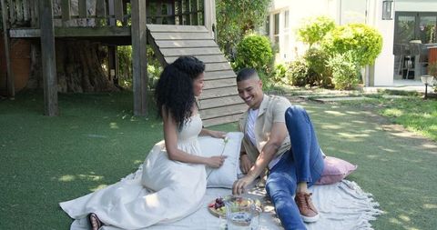 Diverse couple enjoying picnic in sunny backyard