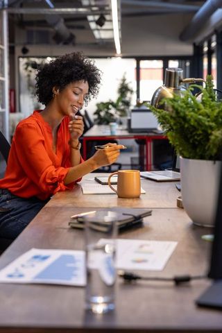 Professional woman writing and using laptop in modern office