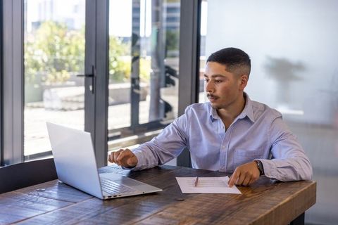 Young professional working laptop in minimalist office setting