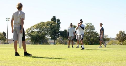Diverse friends playing frisbee on sunny park field for outdoor recreation