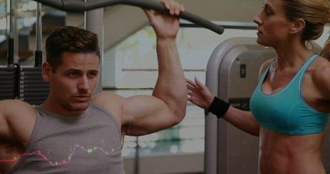 Male trainee pulling lat pulldown while female trainer guiding strength workout form focus