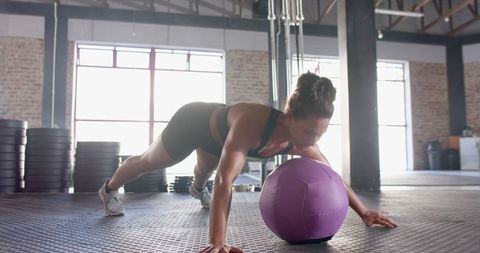 Woman Performing Push-Ups with Medicine Ball in Gym