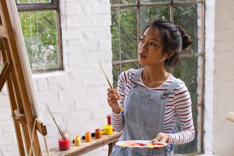 Young Asian Artist Contemplating Canvas in Studio