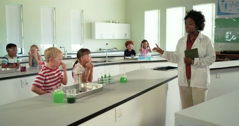 African american teacher leading elementary students in science lab safety and experiment