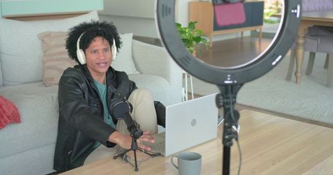 Content creator recording podcast at home with laptop microphone headset and ring light
