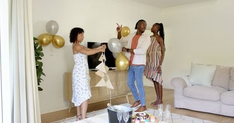 Diverse Friends Preparing Living Room with Balloons for Celebration