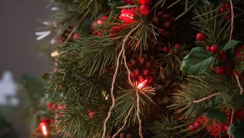 Glowing pine garland with red berries and fairy lights casting warm festive glow indoor