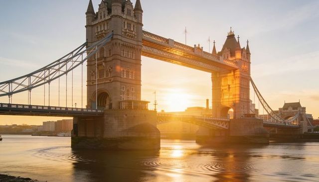 Tower bridge glowing in golden hour light over river thames with soft reflections