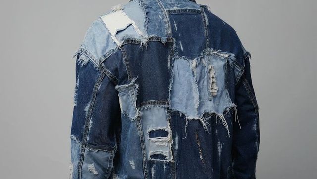 Distressed patchwork denim jacket back view showing textured worn blue menswear style