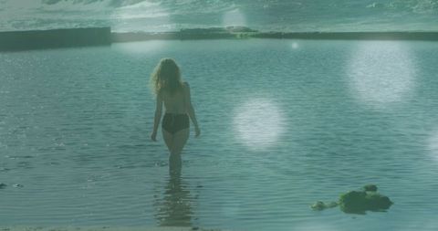 Woman wading in tranquil tidal pool at seaside