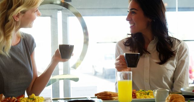 Two women enjoying friendly breakfast conversation in cafe - Download Free Stock Images Pikwizard.com