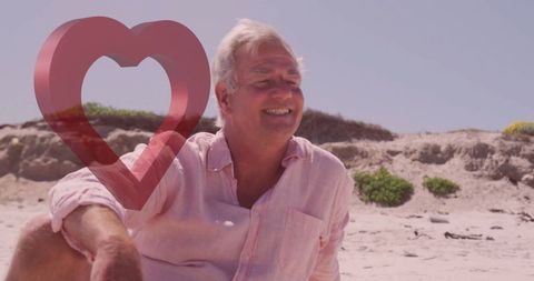 Senior Man Relaxing on Sandy Beach with Heart Shape Symbol