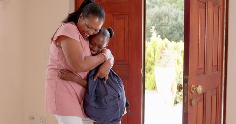 Mother and daughter embracing warmly at home entrance
