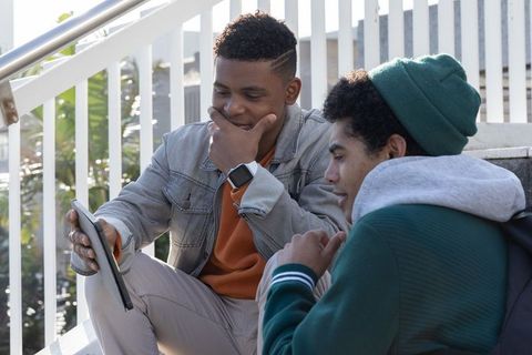 African american teens collaborating on tablet outdoors on concrete steps