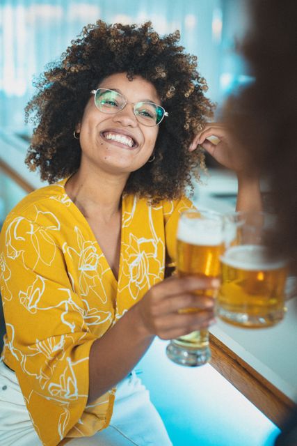 Mixed race woman smiling and drinking beer with friend - Download Free Stock Photos Pikwizard.com
