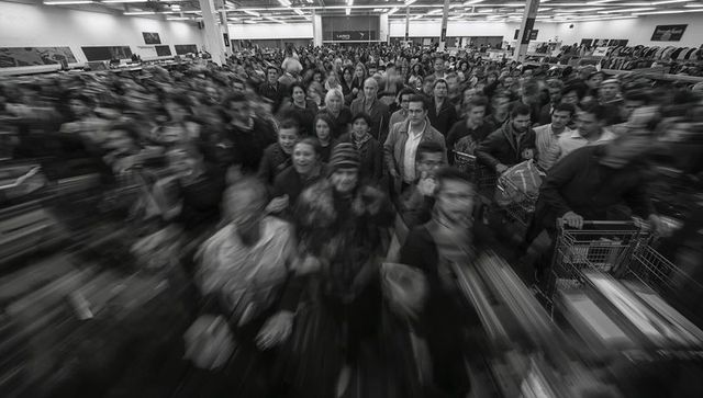Black and white crowd rushing through retail store during major sale event with motion blur