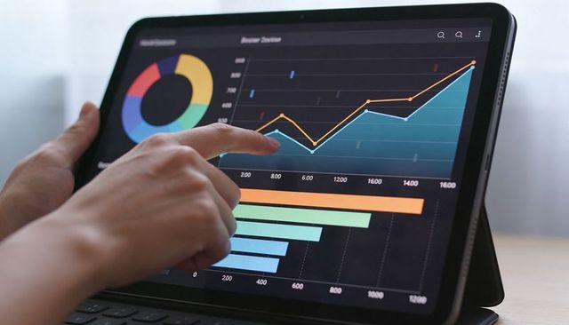 Hands touching tablet selecting interactive analytics dashboard with charts and KPIs