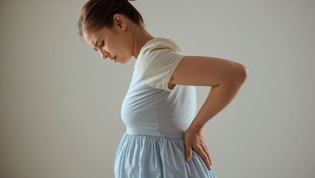 Pregnant woman managing back pain with hand on hip