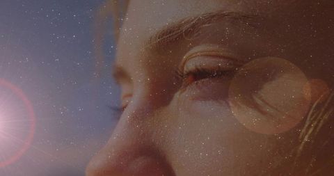 Closeup dreamy portrait of woman squinting into light with star overlay and lens flare