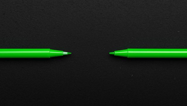 Minimalist design with green ballpoint pens on dark surface