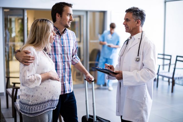 Couple interacting with male doctor in corridor - Download Free Stock Photos Pikwizard.com