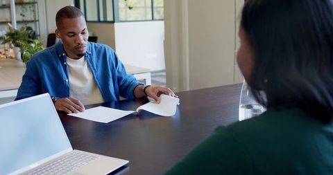 African colleagues reviewing documents at conference table with laptop and glass carafe