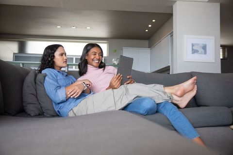 Friends Relaxing on Sofa With Tablet in Modern Home Interior
