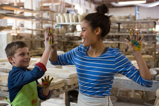 Mother and son giving high five to each other at pottery shop