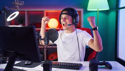 Young gamer celebrating victory on live stream wearing headset backward cap