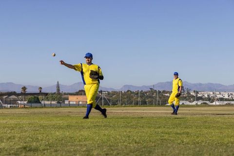 Outfield duo throwing baseball during sunny defensive play with dynamic motion trajectory